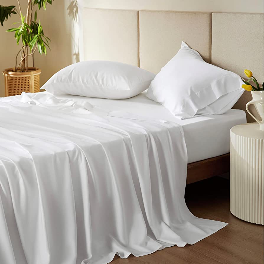 White sheets on a bed with a beige headboard.