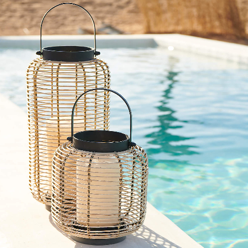 Rattan and black lanterns sit beside a pool on a summer day