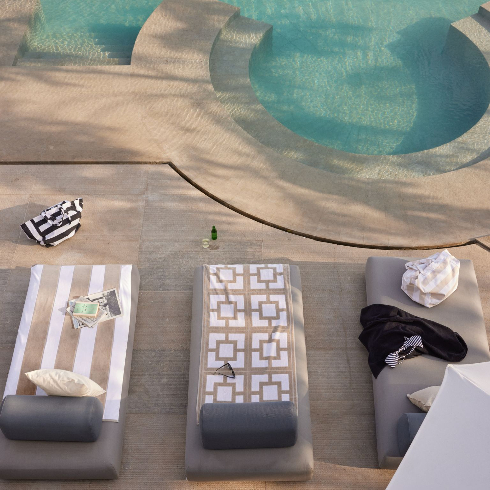 Poolside loungers and a large beach towel near a stunning pool