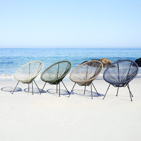 Four outdoor patio chairs in various colours sit in front of blue waters