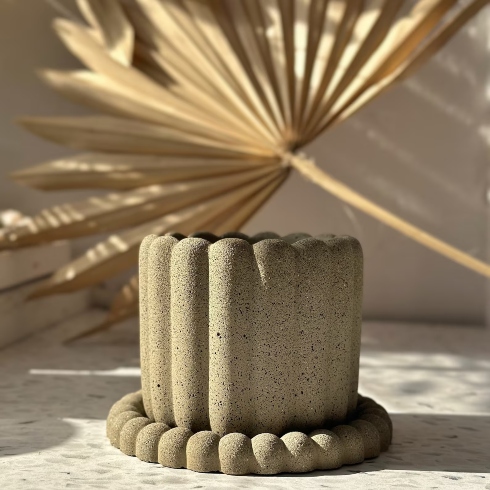A scalloped concrete planter with matching saucer