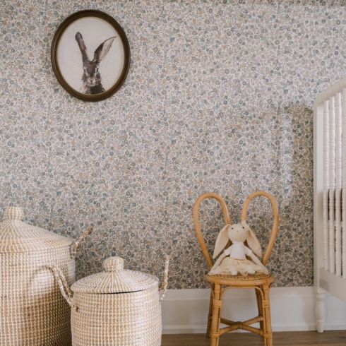 Storage baskets and old-fashioned bunny artwork in wallpapered nursery