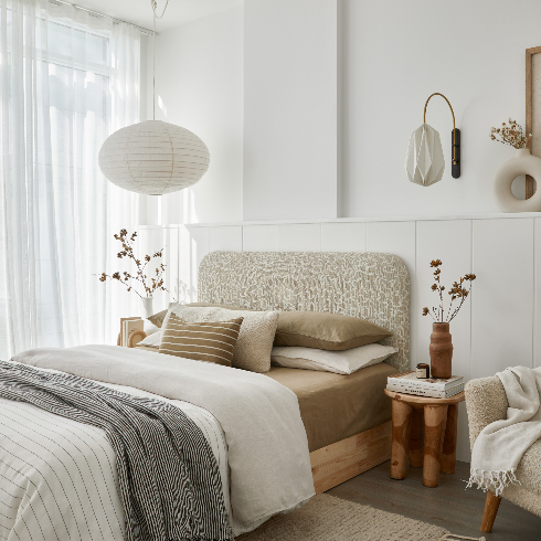 A clean and modern bedroom with white and natural tones and two funky white lamps