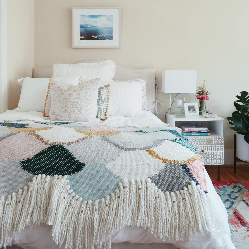 A cozy bedroom with muted colours and a stylish throw on the bed
