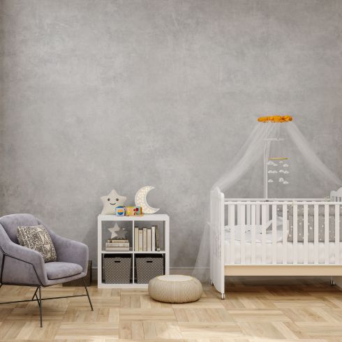 Nursery room with chalky grey walls and white crib, grey chair.