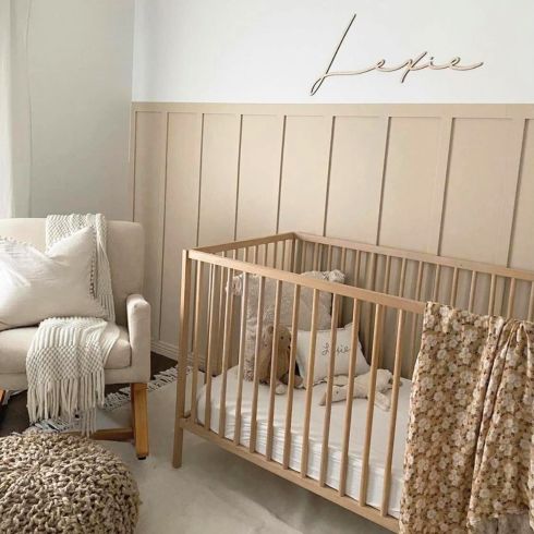 Neutral nursery room with accent wall and name wall decal.