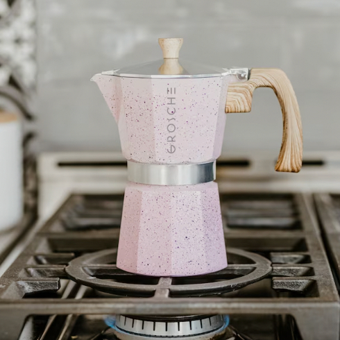 A blush pink stovetop espresso maker on a gas stove