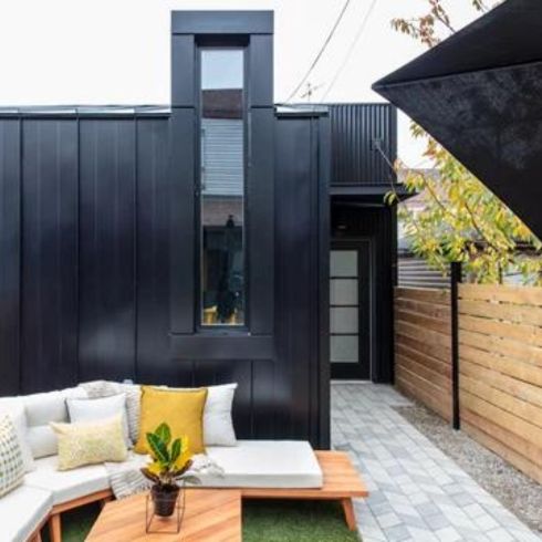 Small backyard with modern furniture and black modern shed.