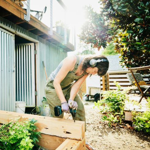 Woman building veggie garden in small backyard