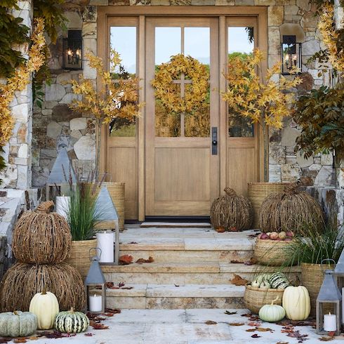 Handcrafted Pottery Barn plush aspen wreath and garland from natural twigs, plastic, polyester, Styrofoam and wire on an exterior door and front steps with twigs pumpkins and pillar candle lanterns