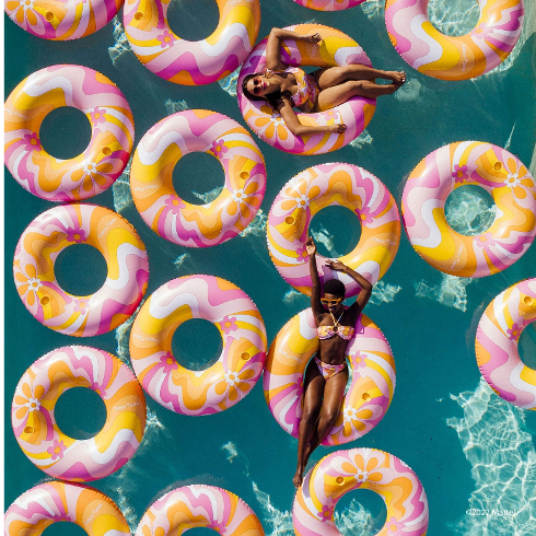 A pool filled with retro floaties and two happy bikini-clad girls lounging in them