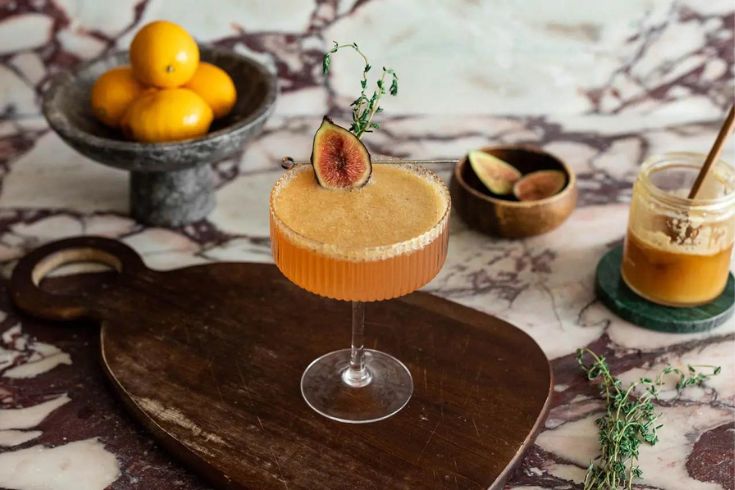 fig and honey prosecco cocktail with fig and herb garnishes.