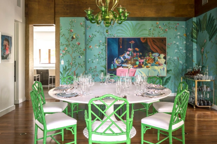 A dining room with light green walls, a round white table and green and white chairs