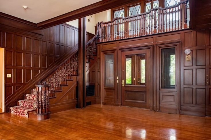 The entranceway inside Copper Beach Farm's main house, with cherry-hued wooden floors, staircase and bannisters.