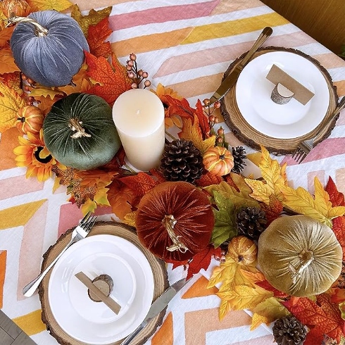A tablescape with two dinner plates and a centrepiece featuring four velvet pumpkins