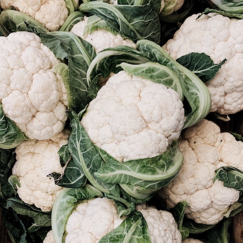 Heads of cauliflower grouped together in pile.