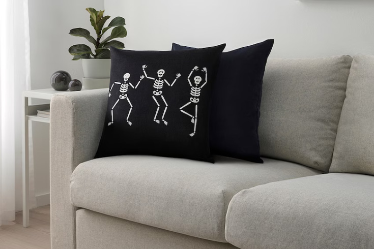 Black skeleton pillow on gray couch
