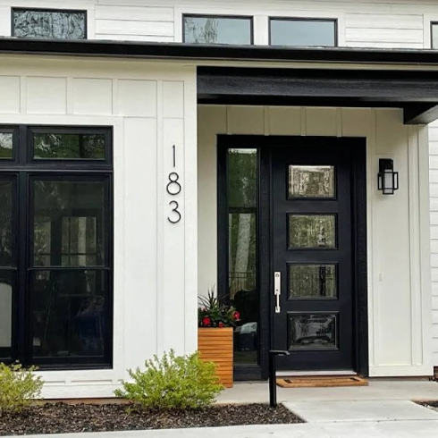 A modern black and white house exterior with large, sans serif numbers