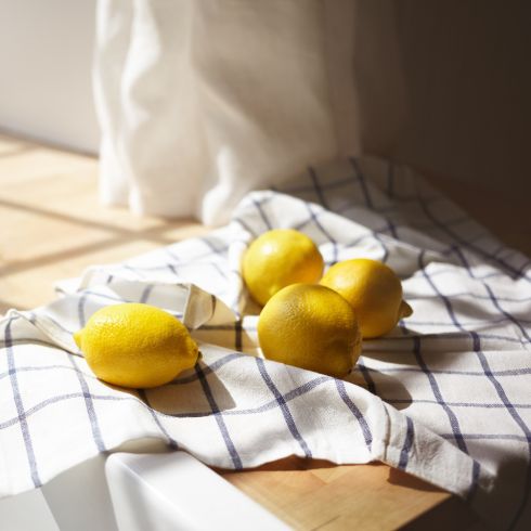 Whole lemons on kitchen tea towel on wooden counter