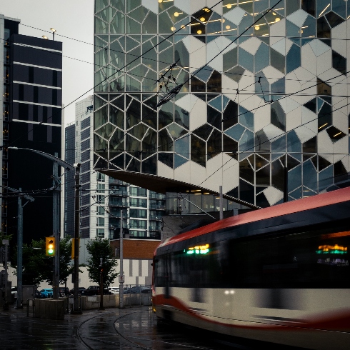 A red and white streetcar passing the new Calgary Central Library in Canada