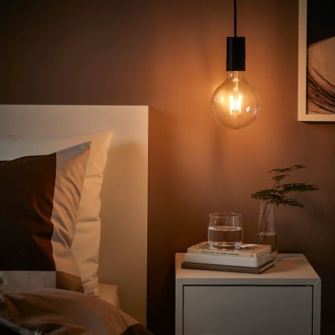 Dim bedroom with modern black hanging pendant lamp.
