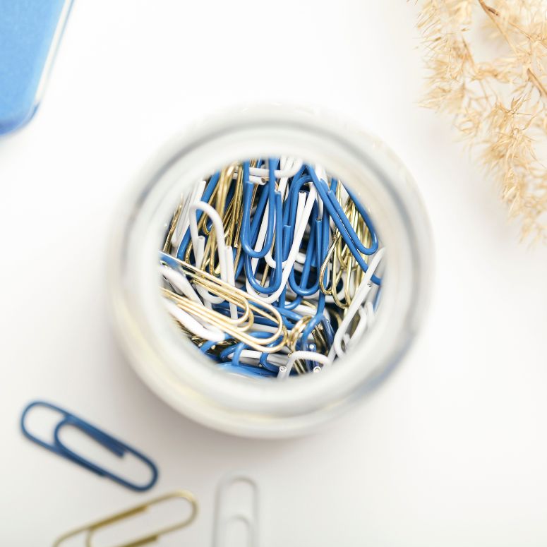 Glass jar of colourful blue and white paper clips