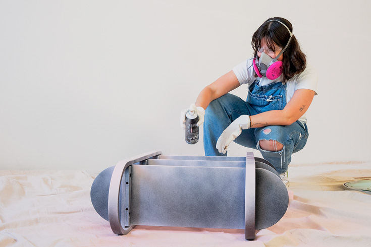 DIY expert Maca spray painting a bathroom shelf with spray paint from Behr
