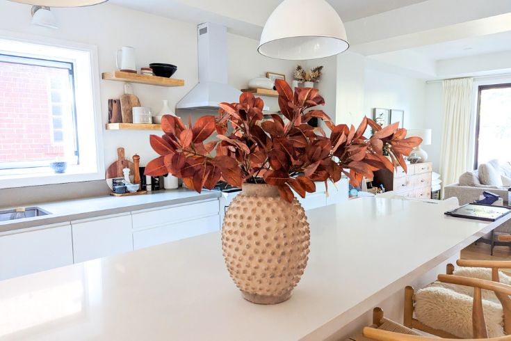 Red faux fall foliage in beige vase in modern white kitchen