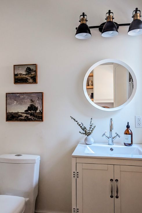 Modern white bathroom with vintage-inspired art above toilet