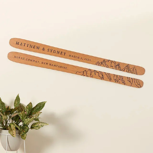 A pair of personalized engraved wooden skis hung to the wall