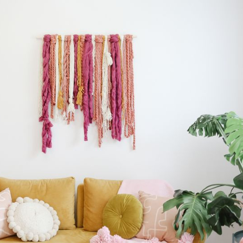 A colourful wall hanging above a yellow velvet couch