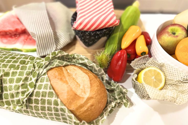 Beeswax food wraps covering baked bread and other produce on kitchen counter