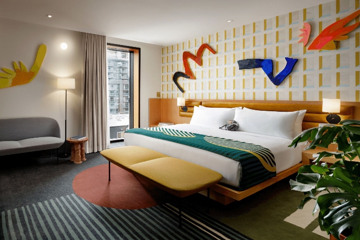 A retro-inspired hotel room with midcentury modern furnishings and bright pops of colour.