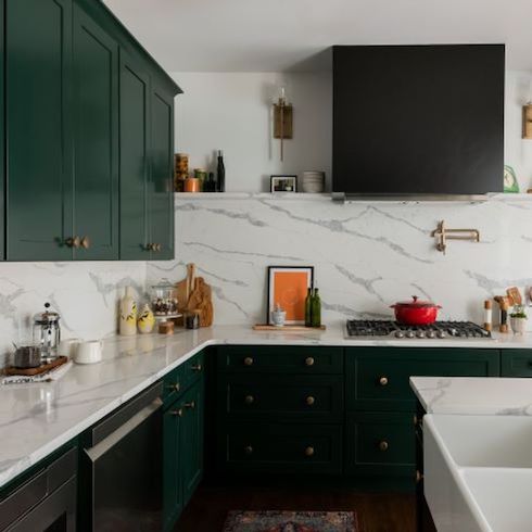 Dark green shaker style cabinets with gold hardware and grey veined white marble countertops and backsplash feature in a chic kitchen renovation by Kortney Wilson for HGTV Canada
