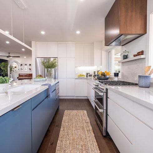 Jonathan and Drew Scott designed and built this kitchen renovation for HGTV Canada’s Property Brothers: Forever Home and features white floor to ceiling cabinetry, a blue kitchen island, and a hidden small appliance garage for a super minimalist kitchen design