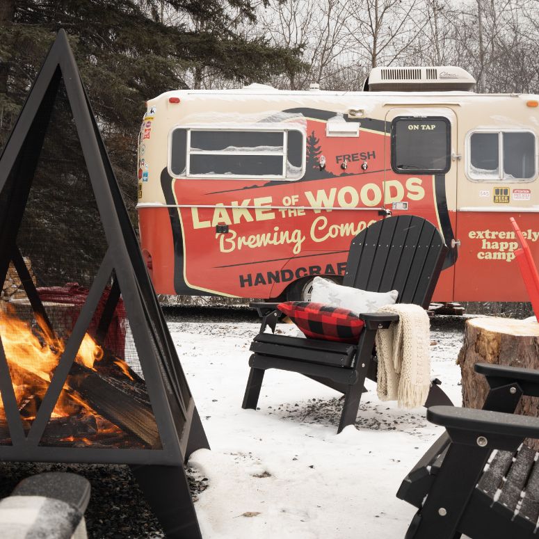 Lake of the woods retro rv next to fire pit with Muskoka chairs