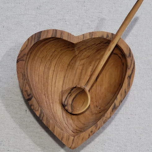 A heart-shaped wooden bowl with a wooden spoon