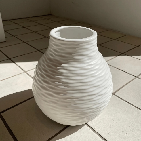 A large, wave-textured white vase