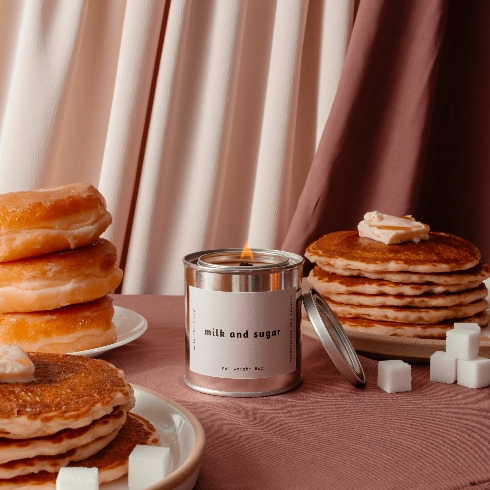 A table with a candle, two stacks of pancakes and a stack of donuts