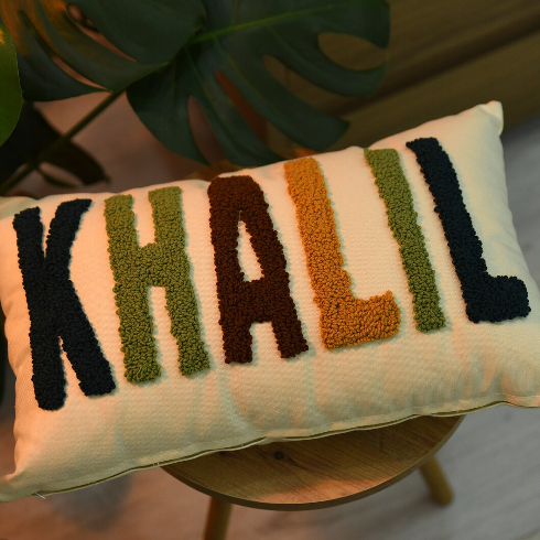 A custom embroidered pillow with the name Khalil in different coloured letters