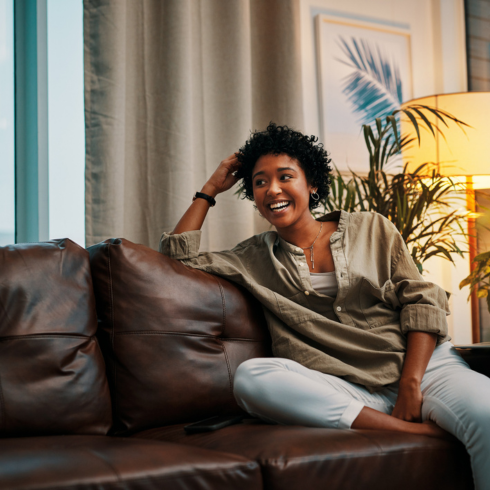 a young Black woman smiling on a leather couch