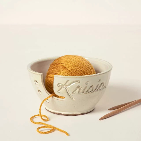 A personalized ceramic yarn bowl with a name etched in