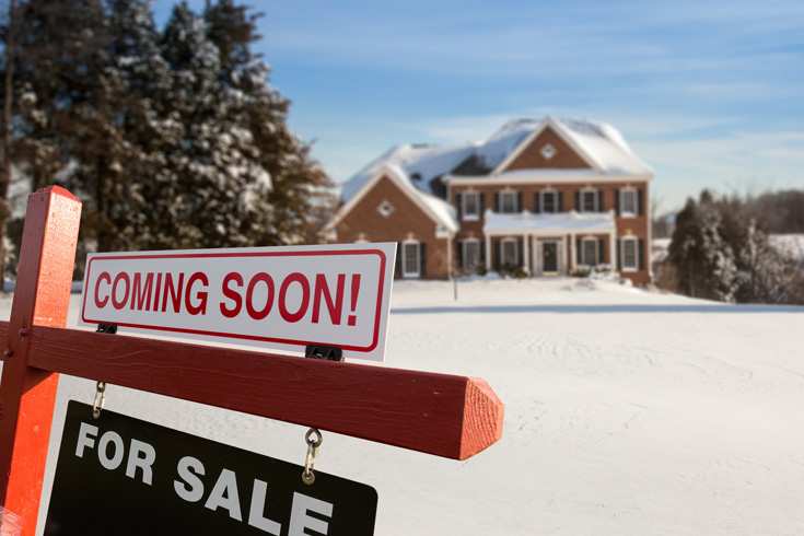 House with a coming soon for sale sign surrounded by snow