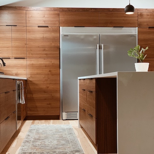 A sleek kitchen with a wall of wooden cabinets and a large kitchen island