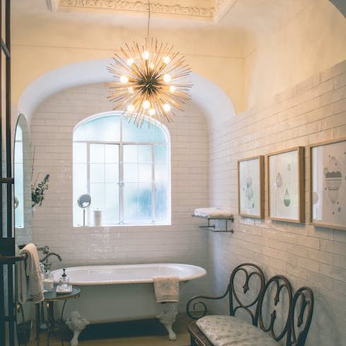 A cozy bathroom with an arched wall and a chandelier