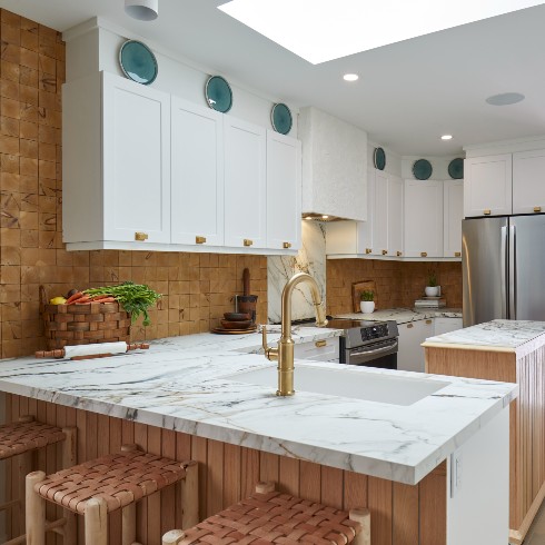 A spacious kitchen with white cabinets and a two types of backsplash materials