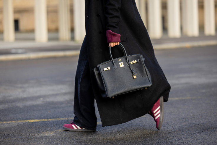 Girl wears black coat, burgundy pullover, grey jeans, sneakers, black bag Hermes Birkin