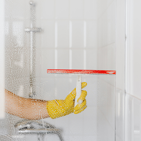 Crop person cleaning glass shower unit