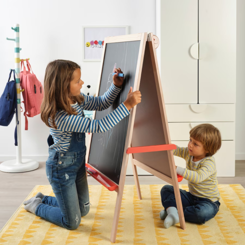 two kids creating art on a double-sided easel