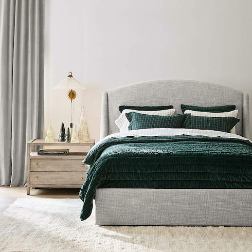 Crate & Barrel Organic Cotton Flannel Spruce Green Windowpane Duvet Cover on an upholstered grey bed in a chic bedroom with white walls, tall grey drapes, wood floors with a plush cream coloured rug, a grey wood bedside table with decorate mercury glass trees and a wall scone